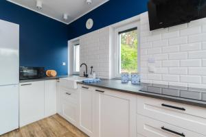 a kitchen with white cabinets and blue walls at Flatbook Apartamenty - Sztutowo Dom Morska in Sztutowo