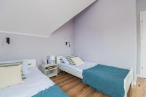 two beds in a room with white walls and wooden floors at Flatbook Apartamenty - Sztutowo Dom Morska in Sztutowo