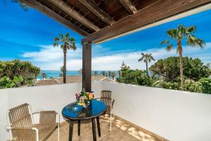 a table on a balcony with a view of the ocean at All About Puente Romano Penthouse Suite in Marbella