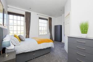 a bedroom with a bed and a dresser and windows at Derby Cathedral Town House - 2 mins walk to city - FREE secure parking in Derby