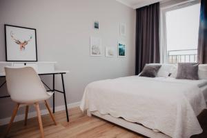 een witte slaapkamer met een bed, een bureau en een stoel bij JBHotels Apartament Prestige in Szczecin