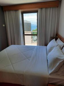um quarto com uma grande cama branca e uma janela em Cobertura no melhor lugar de Ipanema (03) no Rio de Janeiro