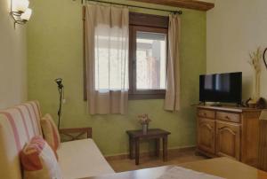 sala de estar con TV y ventana en Las Aliagas Apartamentos Rurales, en Megina
