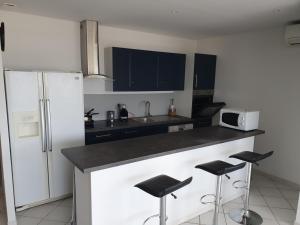 a kitchen with black cabinets and a counter with stools at T4 Front de mer Valras Plage in Valras-Plage