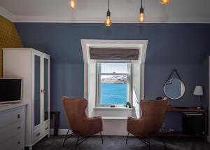 ein blaues Zimmer mit 2 Stühlen und einem Fenster in der Unterkunft Barriemore Oban in Oban