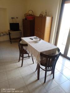 mesa de comedor con 2 sillas y mantel blanco en Casa Vacanze " MELA ", en Nova Siri