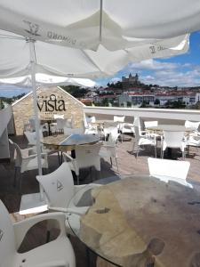 a patio with tables and chairs and white umbrellas at 5ª Vigia in Porto de Mós