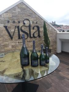 four bottles of wine on a glass table in front of a sign at 5ª Vigia in Porto de Mós