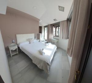Un dormitorio con una gran cama blanca y una ventana en Apartamentos Torre de la Mezquita, en Córdoba