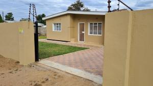 una pequeña casa amarilla con una puerta delante en Stone Villa, en Gaborone