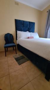 - une chambre avec un grand lit et une chaise bleue dans l'établissement Stone Villa, à Gaborone