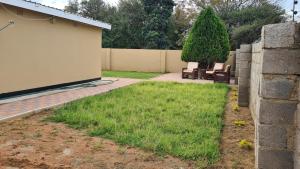 a yard with two chairs and a tree at Stone Villa in Gaborone