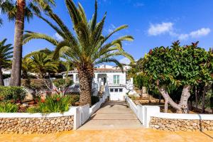 una casa blanca con palmeras y una pasarela en Villa CAN CAULES, en Son Bou