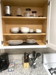 a kitchen cabinet with plates and utensils in it at Cozy and Modern 1BR Apartment with WiFi and Dogs Welcome in Baltimore +17 photos