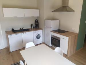 a kitchen with a white refrigerator and a table with chairs at Location à Argentat-sur-Dordogne in Argentat