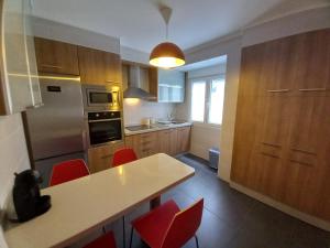 リベイラにあるPrecioso apartamento a 1 minuto de la playaのキッチン(テーブル、赤い椅子付)