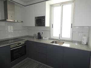 una cucina con armadi grigi, un lavandino e una finestra di O Abeiro do Eume a Pontedeume