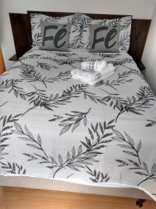 a bed with a black and white comforter with leaves at Plaza Fraga Maia in Feira de Santana