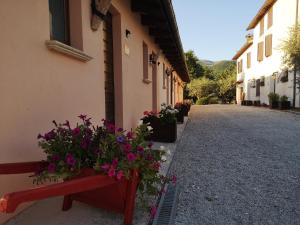 un banco rojo sentado junto a un edificio con flores en Santa Croce, en Fossato di Vico