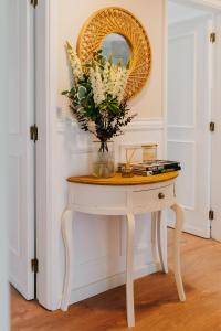 - une table avec un miroir et un vase de fleurs dans l'établissement Villa Rafa, à Costa Nova