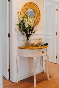 a table with a mirror and a vase of flowers on it at Villa Rafa in Costa Nova