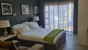 a bedroom with a bed and a chair and a window at Sarona Studio F103 in Gaborone