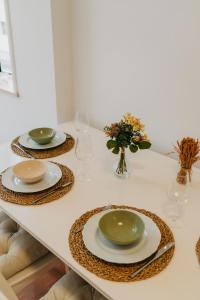 a table with plates and glasses and a vase with flowers at Villa Rafa in Costa Nova