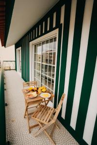 een tafel en stoelen op een balkon met bananen erop bij Villa Rafa in Costa Nova