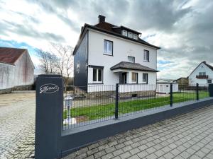 ein weißes Haus mit einem Zaun davor in der Unterkunft Konrads Pension in Solms-Oberbiel