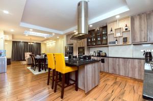 K's Place - Elegant 2 Bedroom Apartment with a Pool & Gym في نيروبي: مطبخ فيه أرضيات خشبية وكراسي صفراء