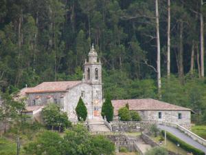 an old stone church with a tower on a hill at Bodega-Enoturismo Lagar De Besada in Xill