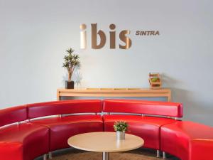 a waiting room with red couches and a table at Hotel Ibis Lisboa Sintra in Sintra