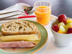 a plate of food with bread and fruit and a glass of orange juice at Hotel Ibis Lisboa Sintra in Sintra