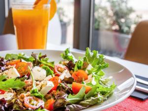 a salad on a plate next to a glass of orange juice at Hotel Ibis Lisboa Sintra in Sintra