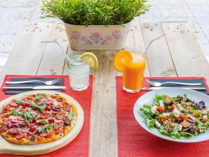 a table with two plates of food and a pizza and salad at Hotel Ibis Lisboa Sintra in Sintra