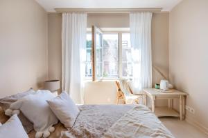 a white bedroom with a bed and a window at Banga & Sunrise Nida in Nida
