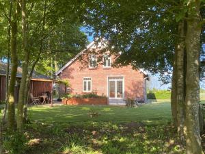 a red brick house with trees in front of it at Hyggelig aftægtsbolig i hjertet af Sønderjylland in Branderup