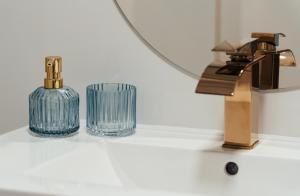 a bathroom sink with a glass bottle and a faucet at Studio Mrągowo in Mrągowo
