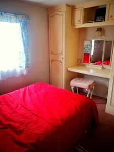 a bedroom with a red bed and a desk at Klarysewo bliżej Słońca in Mrągowo
