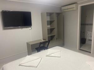 1 dormitorio con TV, escritorio y cama en Pousada Maria`s Inn - Conforto, acolhimento e qualidade em Foz do Iguaçu en Foz do Iguaçu