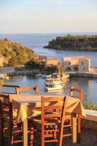 a wooden table with chairs and a boat in the water at Palataki in Kardamyli