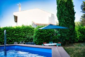 uma piscina com uma mesa e um guarda-sol em Agréable maison 3 chambres avec piscine em Carcassonne