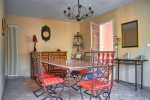una sala da pranzo con tavolo, sedie e orologio di Agréable maison 3 chambres avec piscine a Carcassonne