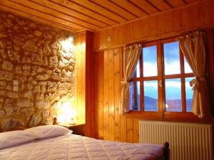 a bedroom with a stone wall and a bed with a window at Ariadne Guesthouse in Arachova