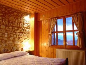 ein Schlafzimmer mit einer Steinmauer und ein Bett mit einem Fenster in der Unterkunft Ariadne Guesthouse in Arachova