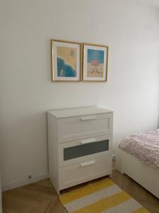 - une chambre avec une commode blanche et deux photos sur le mur dans l'établissement Przytulny apartament, 200m od morza, Gdynia Orłowo, à Gdynia