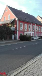 a pink house with a car parked next to a street at Ferienwohnung Murtal in Sankt Lorenzen bei Knittelfeld