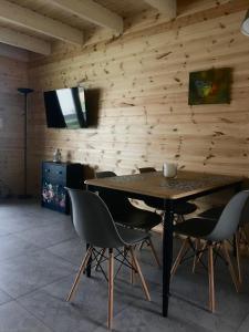 a dining room with a wooden wall with a table and chairs at Domki Wielka Woda in Dywan