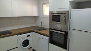 kuchnia z białymi szafkami i pralką i suszarką w obiekcie Atractivo apartamento en la playa con parking w mieście Roquetas de Mar