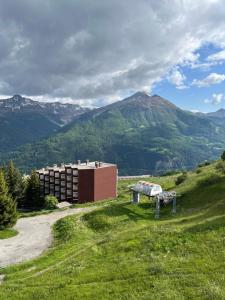 un edificio su una collina con montagne sullo sfondo di Très joli studio au calme et bien situé a Orcières